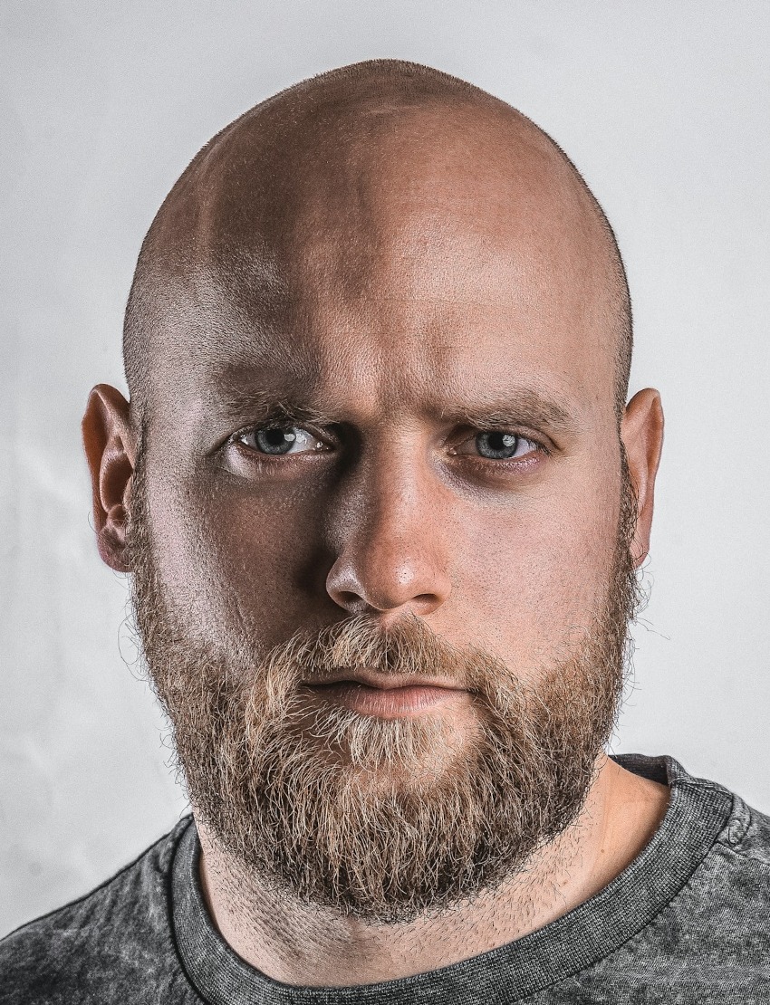Finnish passport file our tool made, 36 x 47 mm: bald, bearded man in a grey crew-neck top on his own light grey wall