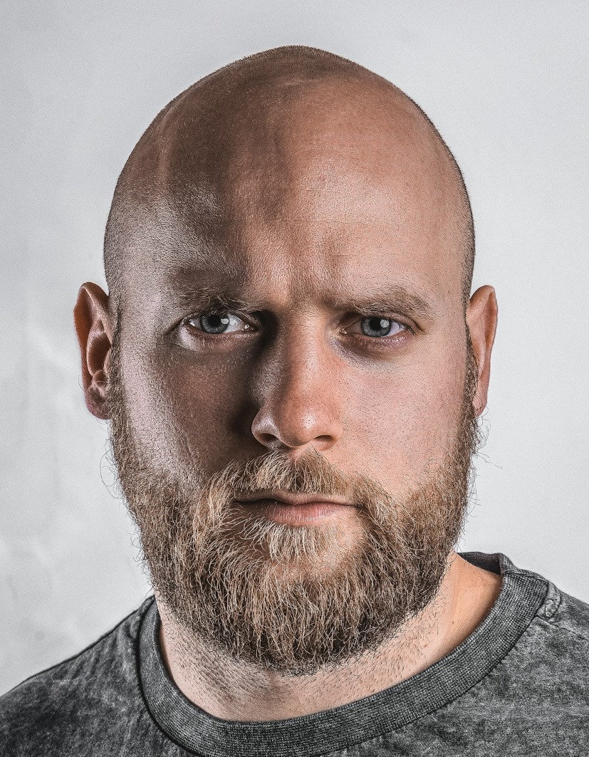 UK printed passport file our tool made, 35 x 45 mm: bald, bearded man in a grey crew-neck top on his own light grey wall
