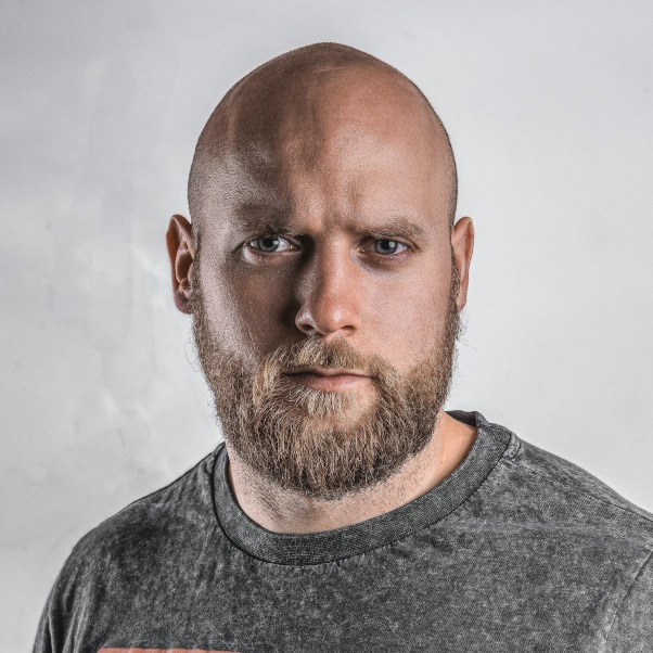 OCI card file our tool made, 51 x 51 mm: bald, bearded man in a grey crew-neck top on his own light grey wall