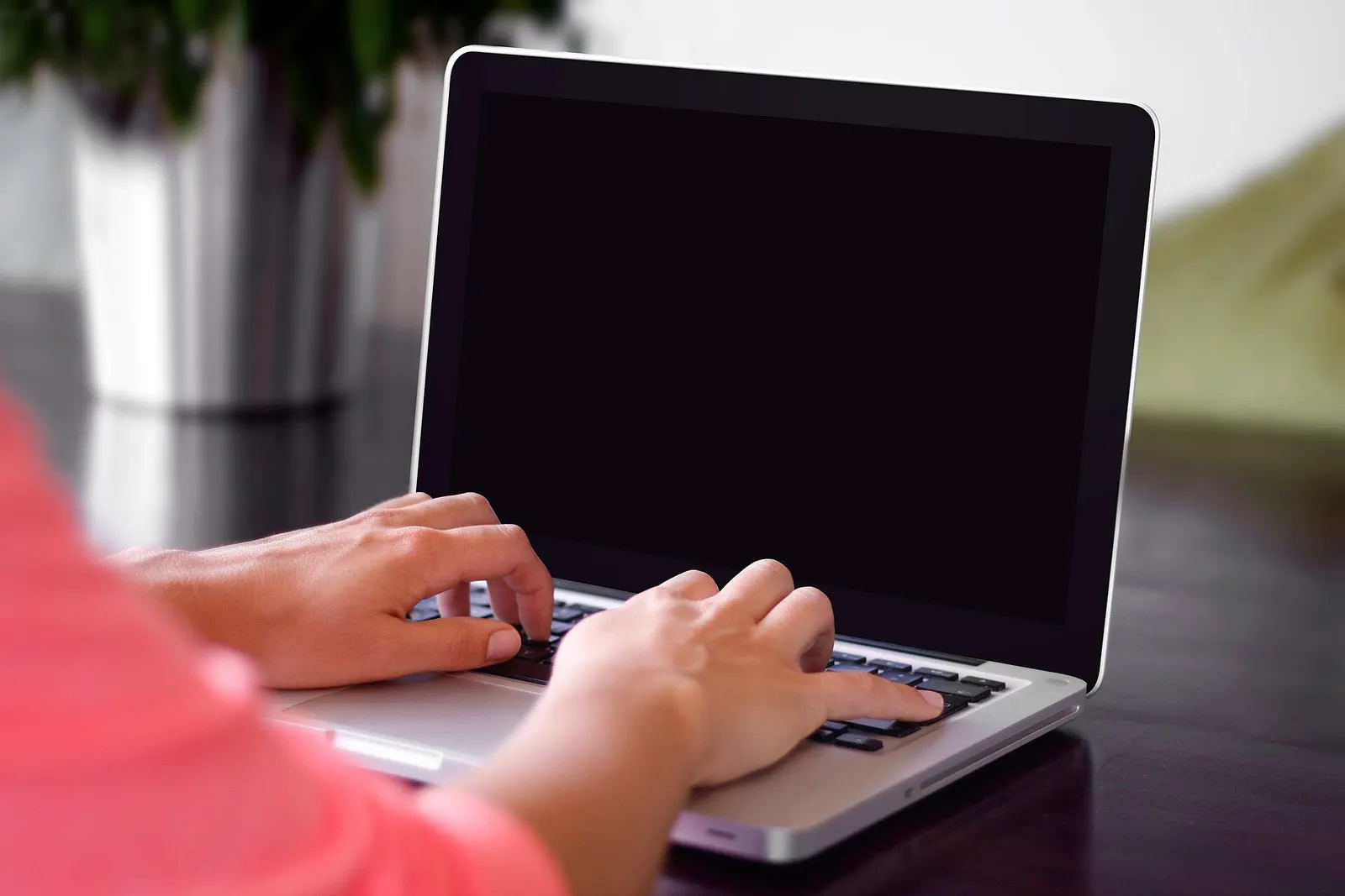 Person typing on a laptop at a wooden table
