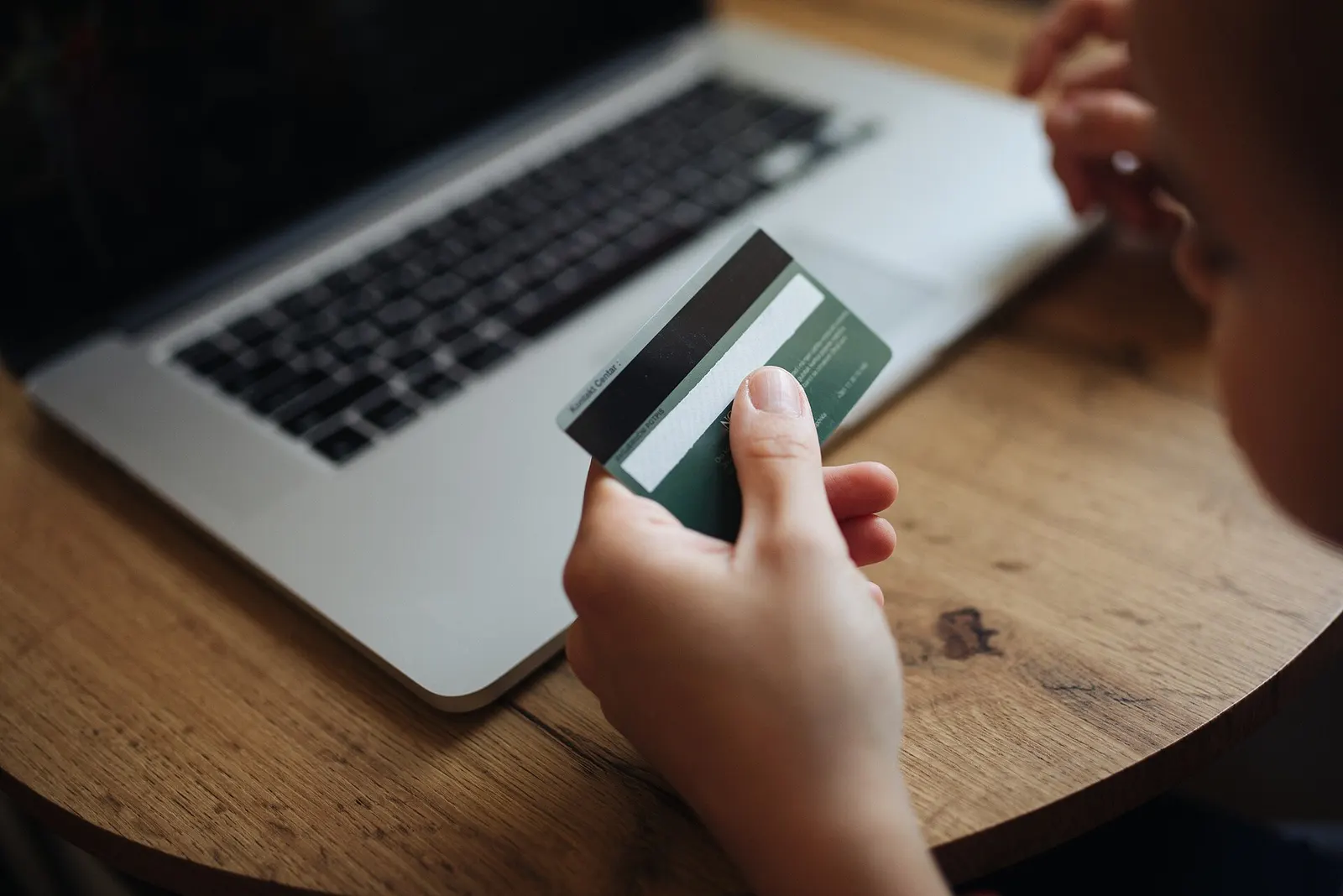 Hand holding a plastic card in front of a laptop